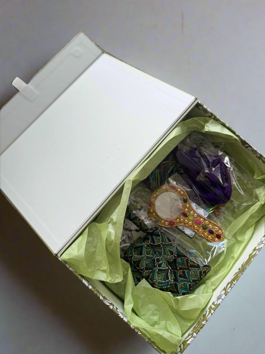 Box with decorative items including a brooch and a small mirror on a textured surface